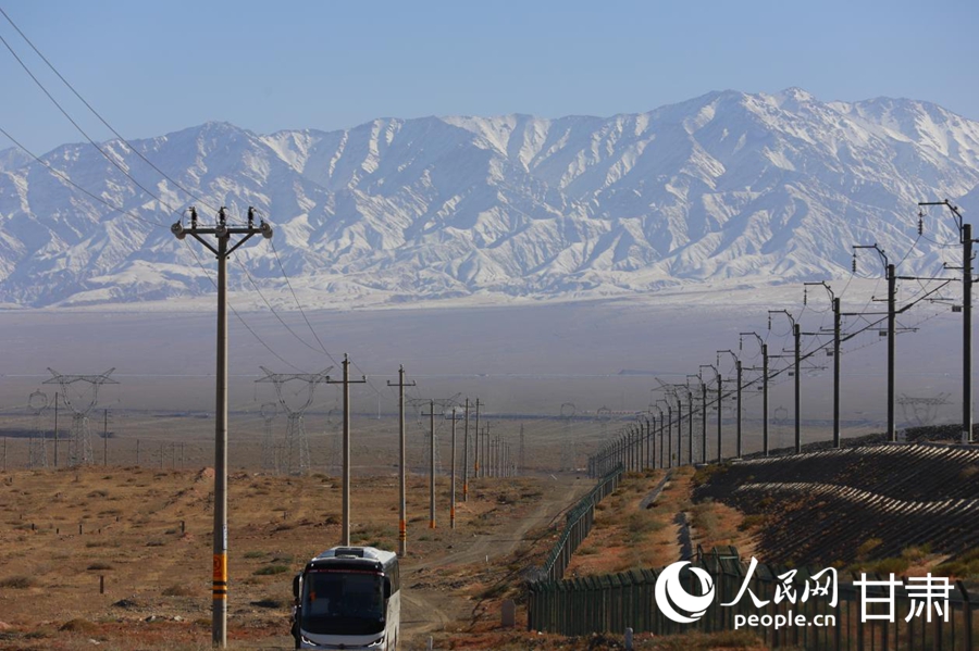 沙山沟铁路特大桥旁的公路，远处是连绵的阿尔金山。人民网记者 焦隆摄